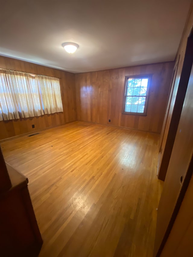 spare room featuring hardwood / wood-style floors and wooden walls