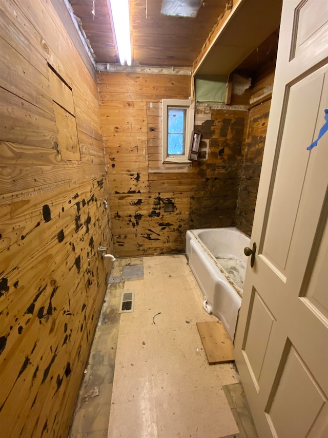 bathroom featuring bathtub / shower combination, wooden walls, and a skylight