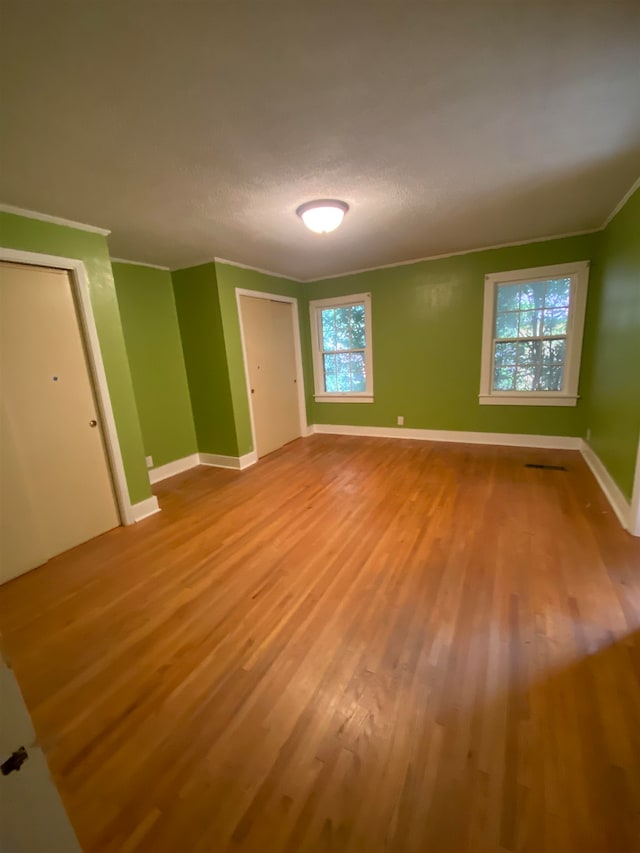 unfurnished bedroom featuring light hardwood / wood-style flooring, ornamental molding, and a textured ceiling