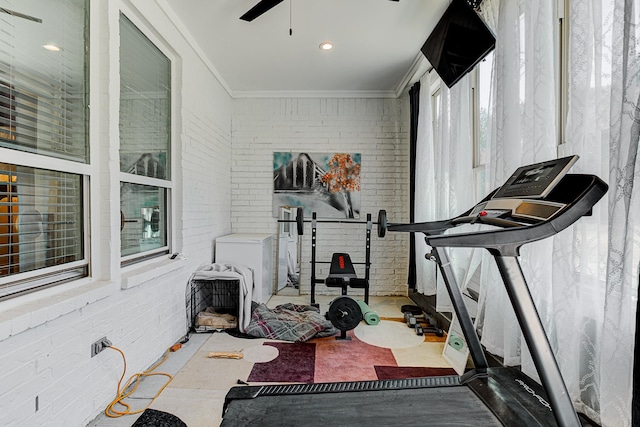 exercise room featuring brick wall, ornamental molding, and plenty of natural light