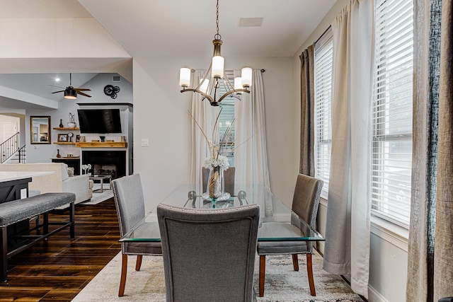 dining space with dark hardwood / wood-style flooring and ceiling fan with notable chandelier