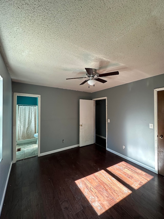 spare room with a textured ceiling, dark wood-type flooring, and ceiling fan