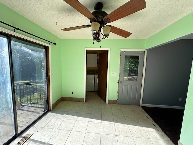 spare room with ceiling fan, a textured ceiling, light tile patterned floors, and washing machine and clothes dryer