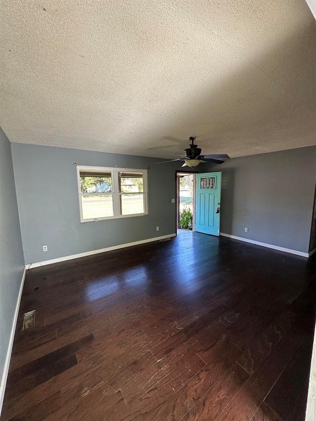 unfurnished living room with a textured ceiling, a wealth of natural light, and dark hardwood / wood-style flooring