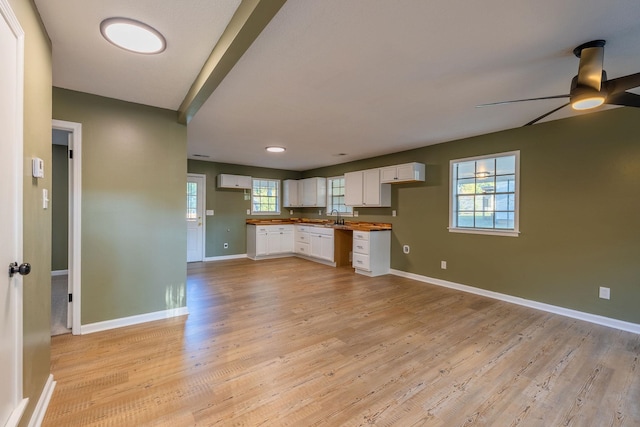 kitchen with white cabinets, ceiling fan, light wood-type flooring, butcher block counters, and sink