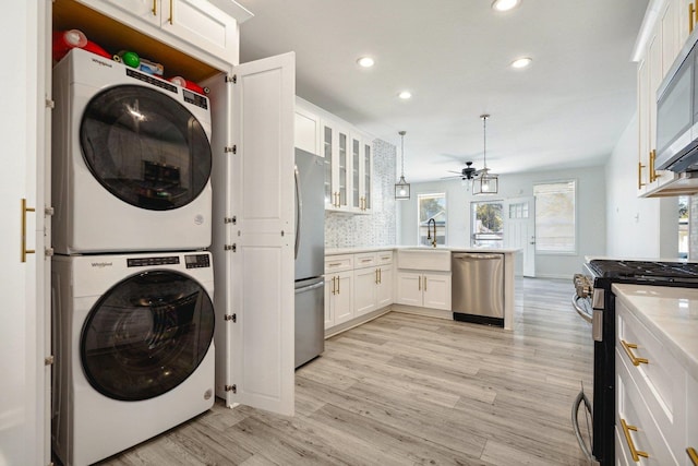 laundry room featuring sink, light hardwood / wood-style floors, stacked washer and dryer, and ceiling fan