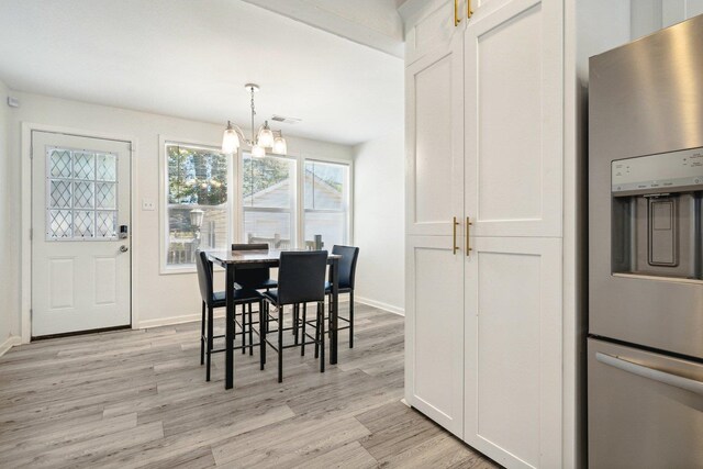 dining space with light hardwood / wood-style flooring and a notable chandelier