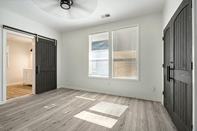 foyer with a barn door, light wood-type flooring, and ceiling fan