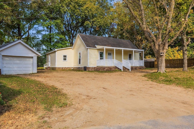 view of front of home with covered porch, a garage, and an outbuilding