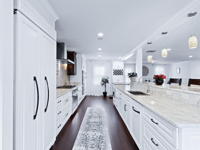 kitchen featuring a large island, sink, dark wood-type flooring, wall chimney exhaust hood, and decorative light fixtures