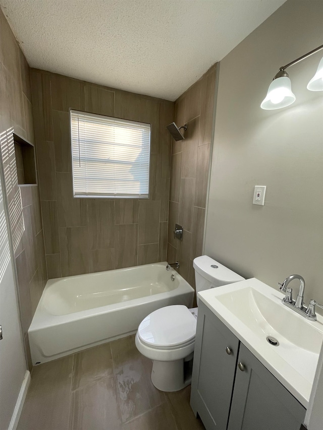 full bathroom with tile patterned floors, toilet, tiled shower / bath combo, vanity, and a textured ceiling