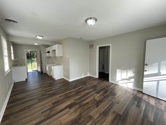 unfurnished living room featuring a textured ceiling and dark hardwood / wood-style flooring