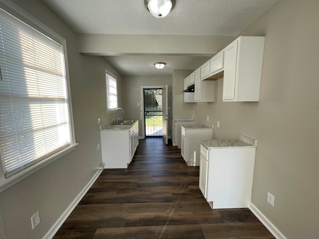 kitchen with sink, a textured ceiling, white cabinets, dark wood-type flooring, and light stone counters