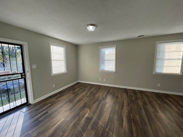 empty room with a textured ceiling and dark hardwood / wood-style floors