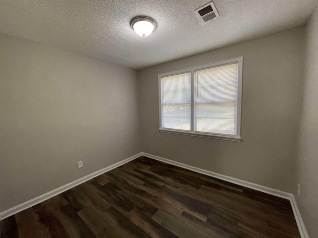 spare room featuring a textured ceiling and dark hardwood / wood-style floors