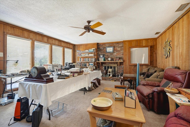 carpeted living room featuring ceiling fan, a textured ceiling, and wood walls