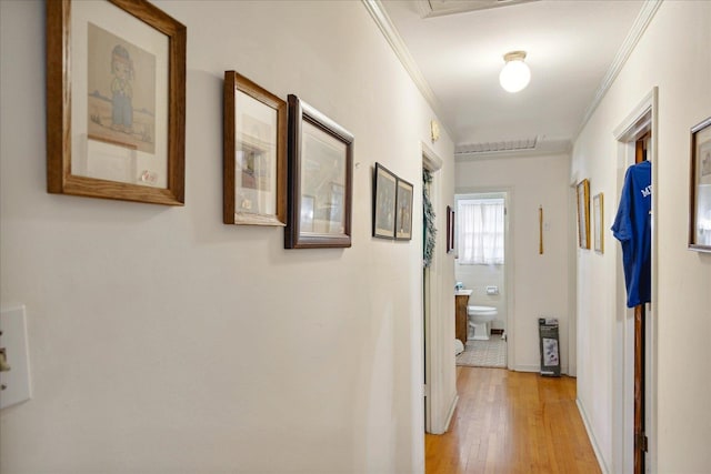 hallway featuring crown molding and light hardwood / wood-style flooring