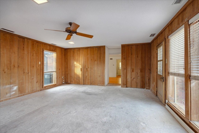 carpeted spare room featuring ceiling fan and wood walls