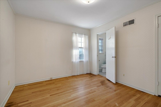 spare room featuring ornamental molding and light hardwood / wood-style floors