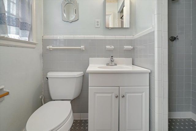 bathroom featuring tile walls, vanity, toilet, and tiled shower