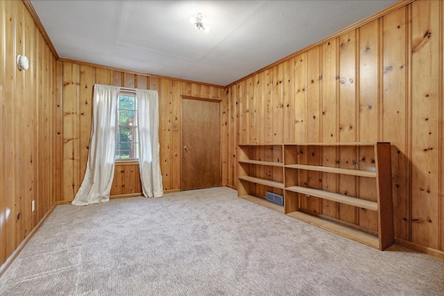 interior space with light carpet, wooden walls, and ornamental molding