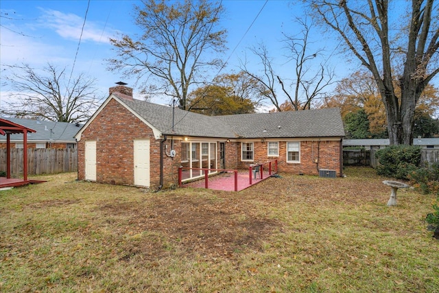 rear view of property featuring central AC unit, a lawn, and a patio