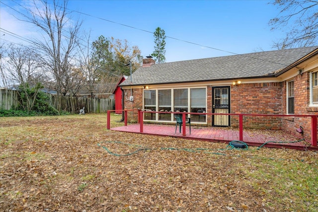 rear view of house featuring a wooden deck and a lawn