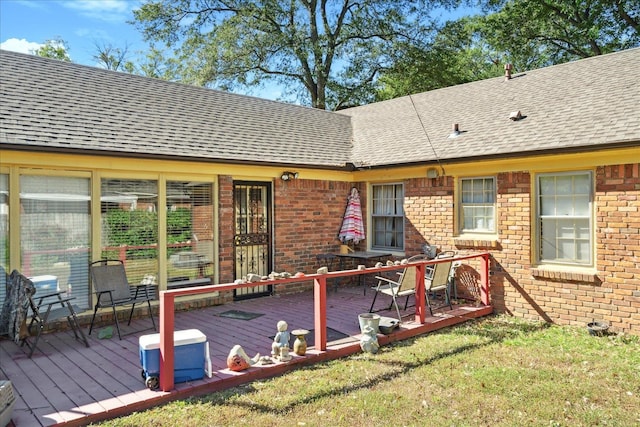 rear view of house featuring a wooden deck and a lawn