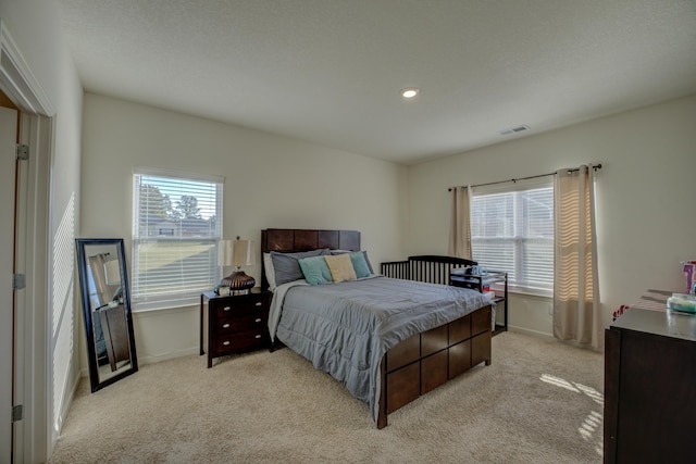 bedroom with multiple windows and light colored carpet