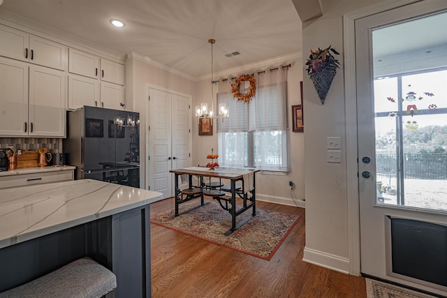 kitchen with black refrigerator with ice dispenser, white cabinets, and plenty of natural light