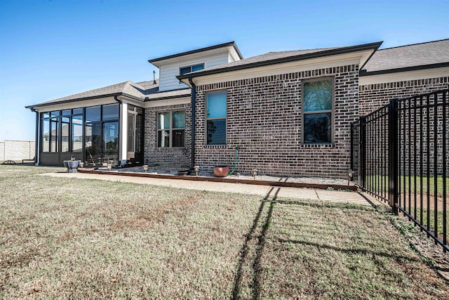 rear view of property featuring a yard and a sunroom