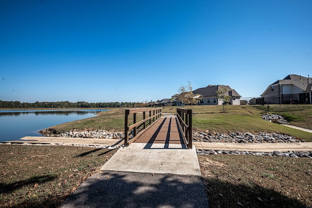 view of dock with a yard and a water view