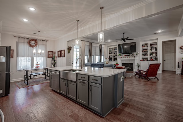 kitchen with sink, decorative light fixtures, gray cabinets, dark wood-type flooring, and a kitchen island with sink