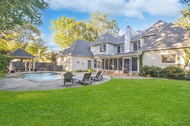 rear view of house with a patio, a chimney, a lawn, a fenced backyard, and a sunroom