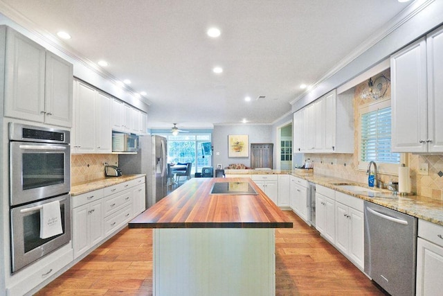 kitchen with decorative backsplash, stainless steel appliances, wooden counters, a sink, and crown molding