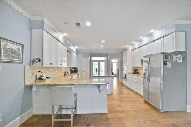 kitchen with crown molding, a sink, visible vents, stainless steel appliances, and a peninsula