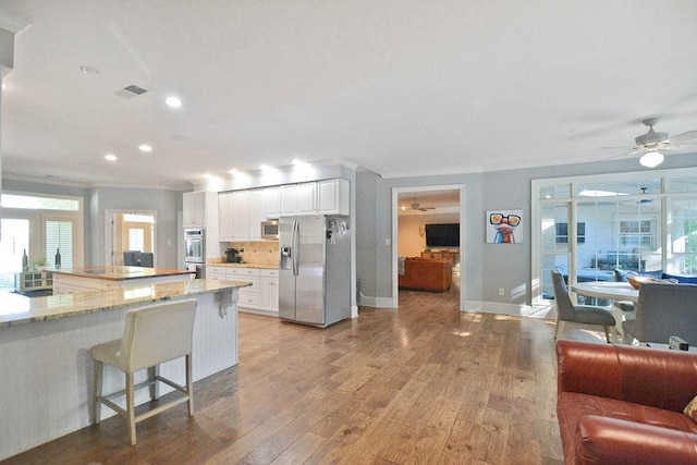 kitchen with recessed lighting, light wood finished floors, stainless steel appliances, a ceiling fan, and open floor plan