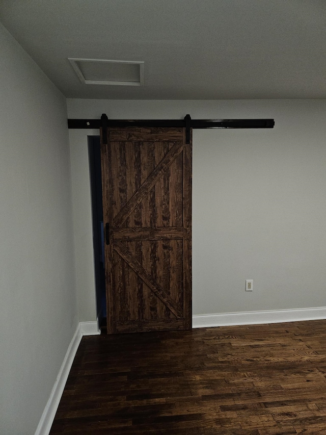 unfurnished room featuring dark hardwood / wood-style floors and a barn door