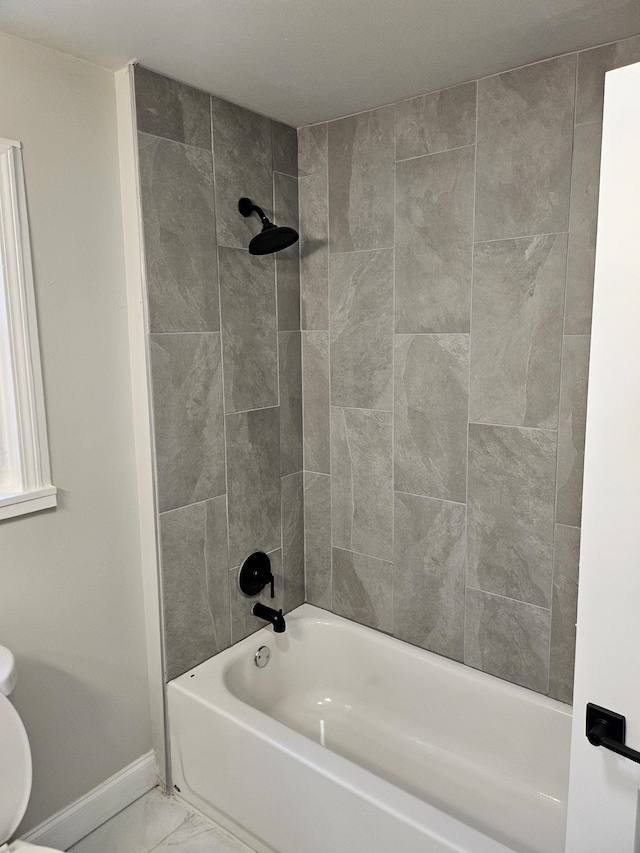 bathroom with toilet and tiled shower / bath