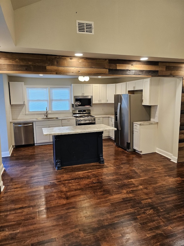 kitchen with a kitchen island, white cabinetry, dark wood-type flooring, and stainless steel appliances