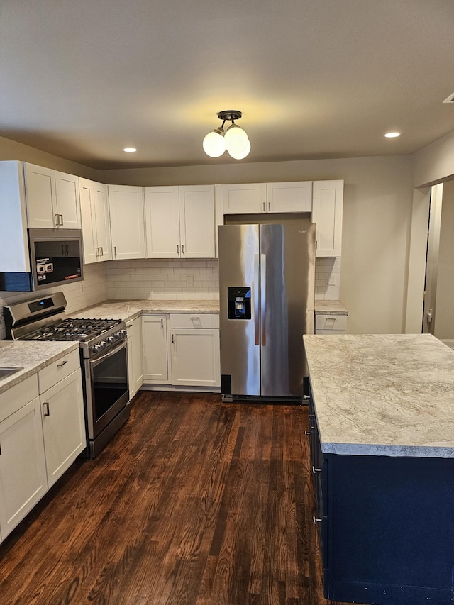 kitchen featuring white cabinets, stainless steel appliances, dark hardwood / wood-style floors, and tasteful backsplash