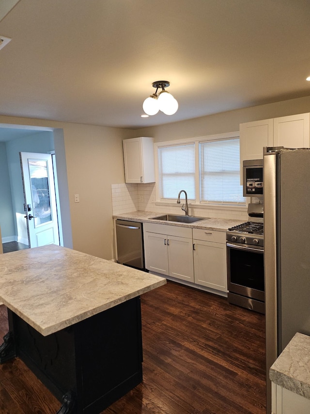 kitchen with tasteful backsplash, sink, dark hardwood / wood-style flooring, stainless steel appliances, and white cabinets