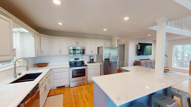 kitchen with a breakfast bar, stainless steel appliances, sink, and white cabinets