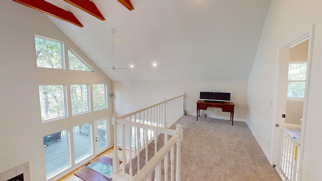 hall with light carpet, beam ceiling, high vaulted ceiling, and plenty of natural light