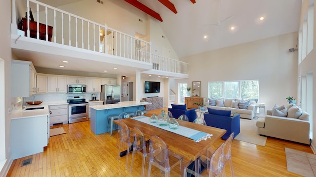 dining area with light hardwood / wood-style flooring and high vaulted ceiling