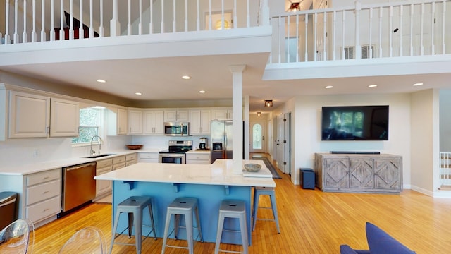 kitchen featuring a towering ceiling, a breakfast bar, stainless steel appliances, and a kitchen island