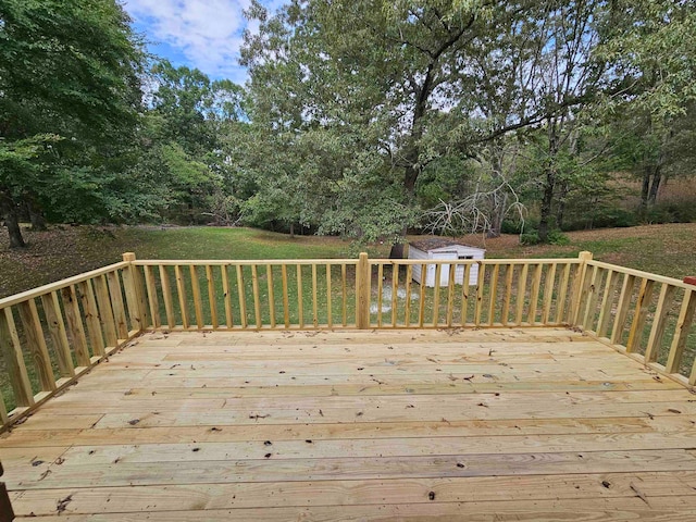 wooden deck with a storage shed and a lawn