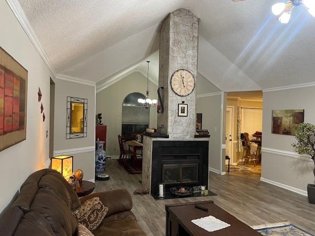 living room featuring crown molding, vaulted ceiling, a fireplace, and hardwood / wood-style floors