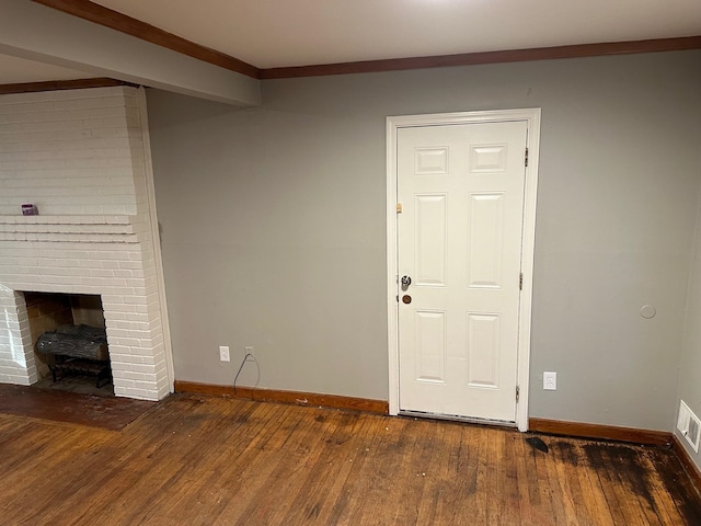 unfurnished living room with ornamental molding, a brick fireplace, and dark hardwood / wood-style flooring