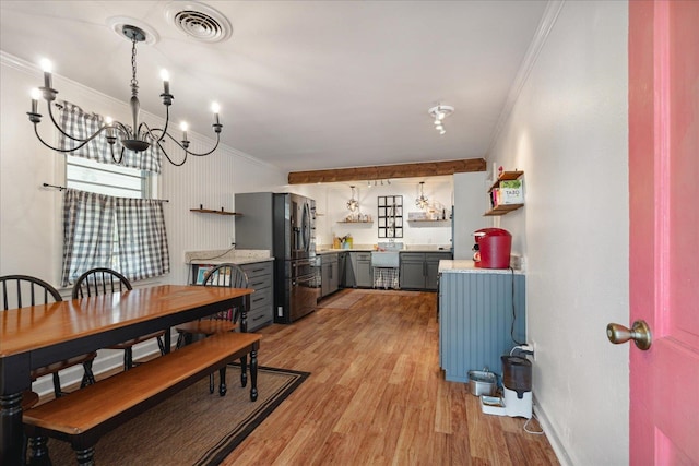 dining space featuring crown molding, a notable chandelier, and light wood-type flooring